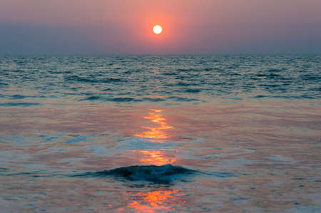 Here you can see a beautiful sunset above the Arabian sea beach and a sea ship far far away behind the horizon . Amazing India.の写真素材