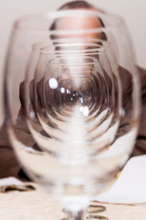 View on man through many empty wineglasses standing in a row one after another