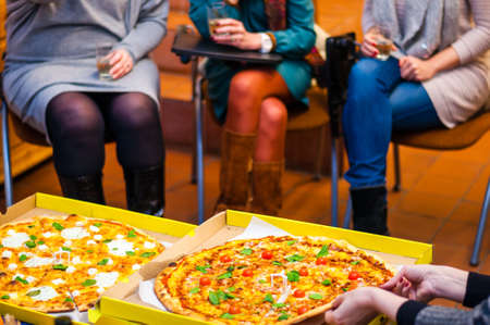 Various tasty and hot Pizza slices on a table sharing between all sitting peopleの写真素材