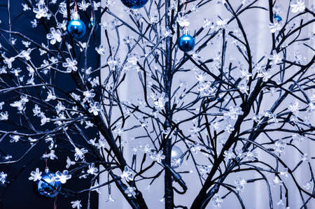 Metal wire woven artificial tree with little flowers lamps and hanging blue chrismass tree glass ballsの写真素材