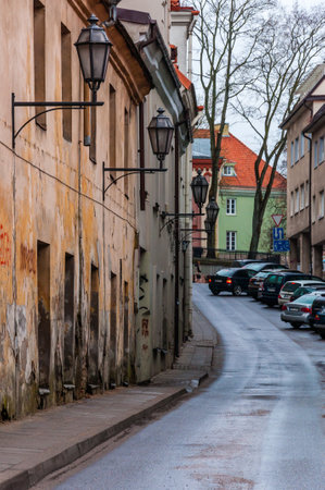 Vilnius, Lithuania - April 28, 2013: Latako street view with parked cars, wall lanterns and old crackyed stucco on the walls in Old Town of Vilnius. Classical European architecture street designのeditorial素材