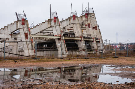 Abandoned stadium concrete reinforcement foundation construction frame shapes with tv-tower in fog on the backgroundの写真素材