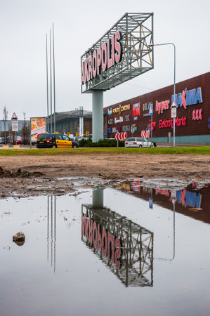 Vilnius, Lithuania - April 28, 2013: Huge and thick metal column and frame with Akropolis Shopping Center logo on it standing near the mall itself with many other brands logo on its facadeのeditorial素材