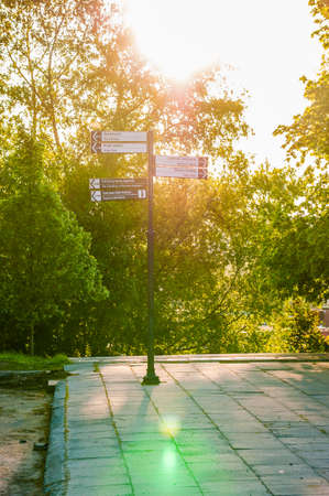 Vilnius, Lithuania - May 15, 2013: The road sign with sunlight from behind surrounded by plants and trees showing the main attractions and important and popular places in Vilnius, Lithuaniaの写真素材