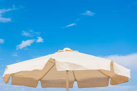 White fabric sun umbrella parasol close-up from below with summer sky on the backgroundの写真素材