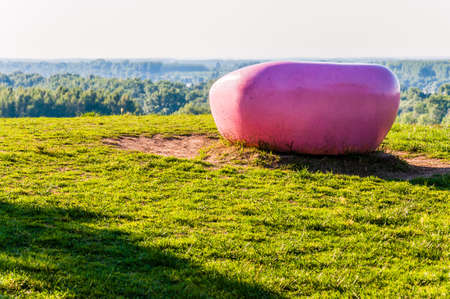 Pink painted round flat stone laying on the hill with scenic panoramic viewの写真素材