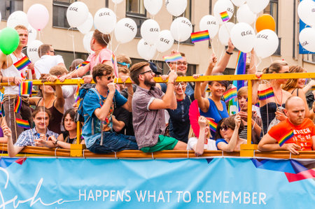 Vilnius, Lithuania - July 27, 2013: Pride parade event in action. Proud and happy people demonstrators standing on yellow open top bus decorated with vibrant and colorful rainbow flags and balloonsのeditorial素材