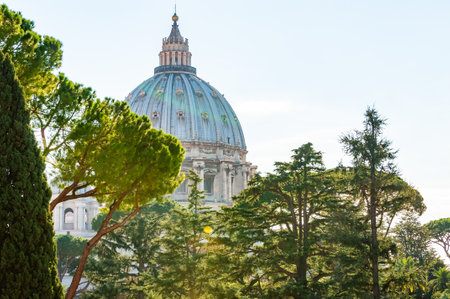 Vatican, Rome, Italy - November 16, 2018: The dome of the Papal Basilica of St. Peter in the Vatican or simply St. Peter's Basilica through the backyard trees. Sunlight illuminating the dome and treesのeditorial素材