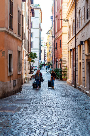 Rome, Italy - November 18, 2018: People walking with their luggage by the ancient medieval Old Town paving stone street in Rome, Italyのeditorial素材