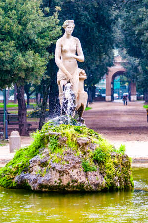 Rome, Italy: Gorgeous rocky stone fountain with sculpture of a woman surrounded by growing plants in Park Borghese in Rome, Italyの写真素材