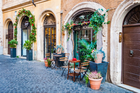 Rome, Italy - November 18, 2018: Arch door entrance of coffee bar called Caffe Novecento decorated with plants and flowers with standing tables and chairs. Cozy places like this many in Romeのeditorial素材