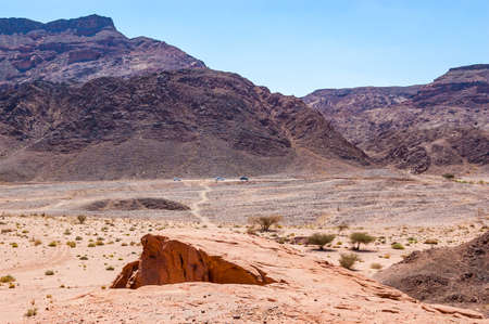 The road, walking path, tracks and trails through the yellow red rocky mountains and landscapes of Timna National Park in Negev desert in Israelの写真素材