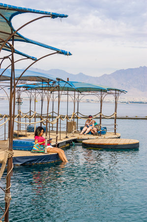 Eilat, Israel - March 21, 2017: On water pavilions and wooden walkways with sitting inside tourists...