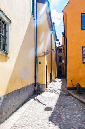 Cozy narrow street with yellow orange buildings facades in Old Town of Stockholm, Swedenの写真素材