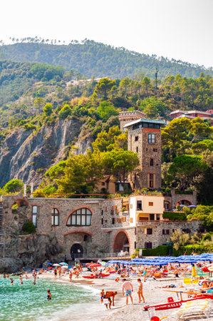 Monterosso Al Mare, Italy - September 02, 2019: The beach full of people, colorful waterfront buildings and green rocky mountains on the background in Monterosso Al Mare, Cinque Terre, Italyのeditorial素材