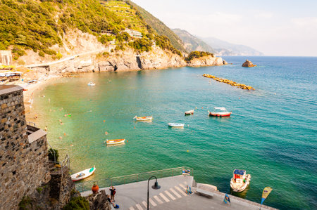 Monterosso Al Mare, Italy - September 02, 2019: Rocky coastline with floating boats and the beach with resting tourists in Monterosso Al Mare, Cinque Terre, Italyのeditorial素材