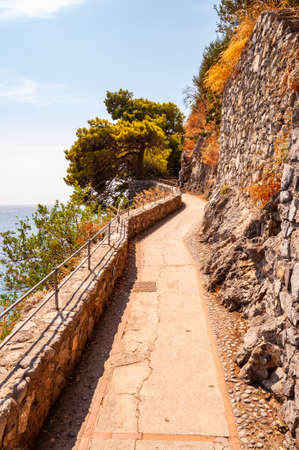 Scenic promenade on the edge of rocky mountain and Tyrrhenian sea bay in Positano, Italy. Boats floating near the rocky coastの写真素材