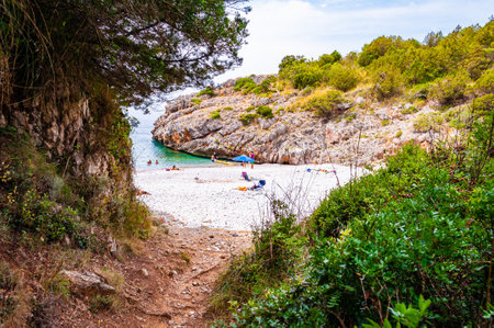 Cala Bianca, Italy - September 06, 2019: One of a couple secret entrances to amazing Cala Bianca beach surrounded by rocks and Tyrrhenian sea bay with crystal clear deep water full of underwater lifeのeditorial素材