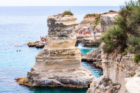 Tropea, Calabria, Italy - September 09, 2019: People diving from the flat cliff, sunbathing, swimming in crystal clear sea water on the rocky beach Torre Sant Andrea with rocks, cliffs and sea stacksのeditorial素材