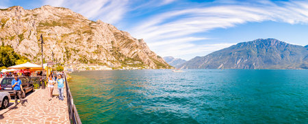 Limone Sul Garda, Lombardy, Italy - September 12, 2019: Panorama of beautiful Garda lake in Lombardy, Italy surrounded by high dolomite mountains. People walking on promenade full of small businessesのeditorial素材