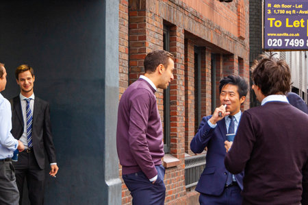 London, United Kingdom - September 14, 2017: Smoking break near the offices. People standing outdoors of their working places during the short break, talking to each other, smoking, drinking coffee.のeditorial素材