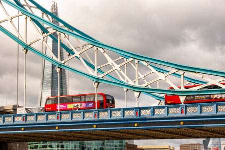 London, United Kingdom - September 14, 2017: Classic red London buses crossing the vibrant and colorful fragment of the famous Tower Bridge in London with the Shard skyscraper on the backgroundのeditorial素材