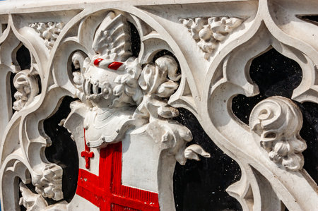 London, United Kingdom - September 14, 2017: Classic decorated bent design fragment of the railing with red painted flag of England in London. White paint on concrete constructions of the fence.のeditorial素材