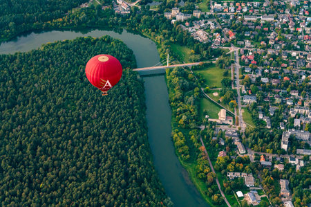 Vilnius, Lithuania - September 14, 2021: Vibrant red hot air balloon flying above Vilnius capital of Lithuania. Zverynas district and Vingis park surrounded by Neris river.のeditorial素材