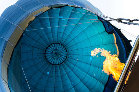 Vibrant powerful flame filling blue bulb textile of balloon with hot air for take of to the skyの写真素材