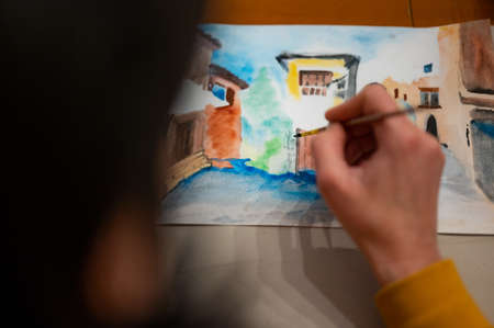 Process of creative art workshop. Artist painting colorful architecture cityscape on paper using brush and watercolorsの写真素材