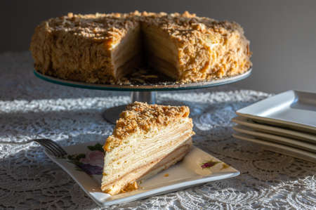 First slice of famous Napoleon cake served on square plate. Triangle slice of cake decorated with...