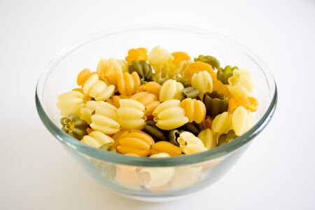 uncooked italian pasta in glass bowl  on white backgroundの写真素材