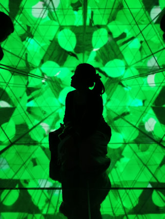 silhouette of a woman in a dark room with green lightsの写真素材