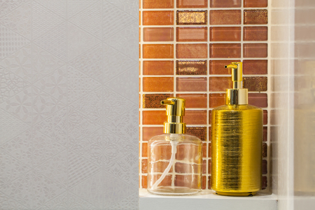 Clear and golden liquid soap bottle with tile background Bathroom accessories.の写真素材