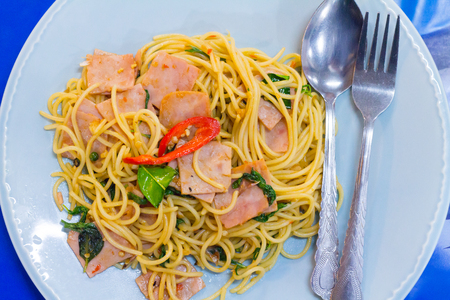 fusion food, spaghetti with fried crispy bacon ,sausage and basil leave, hot and spicy food, international cuisineの写真素材