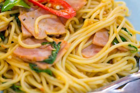 fusion food, spaghetti with fried crispy bacon ,sausage and basil leave, hot and spicy food, international cuisineの写真素材