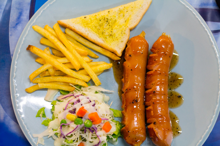 Grilled sausage with sauce and Fresh salad and French friesの写真素材