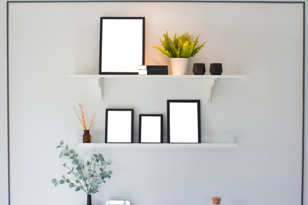 Blank black wooden frame and tree on shelf over white cement wall background, templateの写真素材