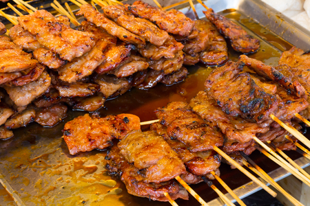 pork on the grill with flame. / Street food in Thailand. / thai style bbq grilled pork./ Grilled pork skewers at night market.の写真素材