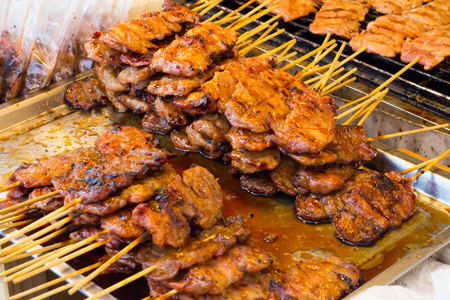 Pork on the grill with flame. Street food in Thailand. Thai style bbq grilled pork. Grilled pork skewers at night market.の写真素材
