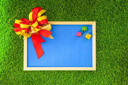 Blue photo frame with ribbon and small colorful box of gift on green grassの写真素材