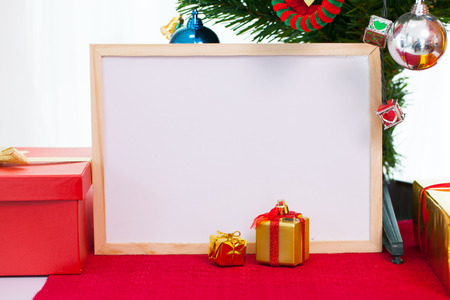 Wooden photo frame with christmas decoration on red carpet. Red boxes gift New year greeting card template.の写真素材