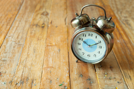 Big vintage alarm clock with bells, painted antique wooden backgroundの写真素材