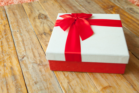 White gift box and red ribbon  on wood background with space.の写真素材