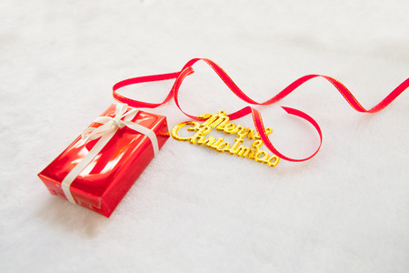 small red gift box and gold merry christmas text with red ribbon