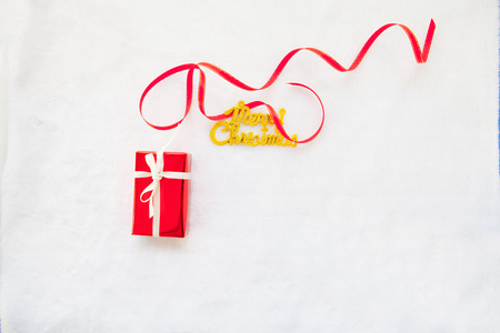 small red gift box and gold merry christmas text with red ribbonの写真素材