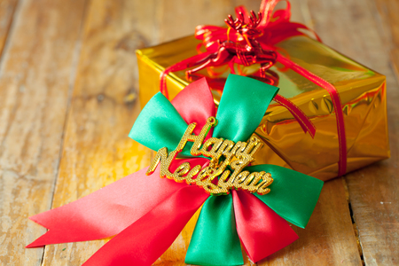 Golden gift box and red ribbon and Happy new year gift on wood background with space.の写真素材