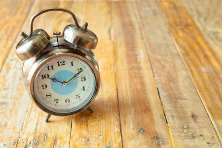 Big vintage alarm clock with bells, painted antique wooden backgroundの写真素材