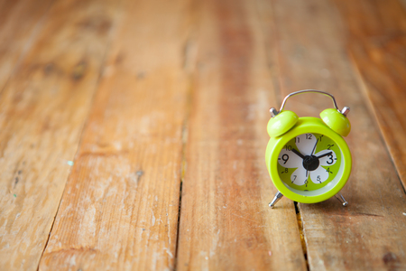 Green small alarm clock on wooden with selective focus and copy spaceの写真素材