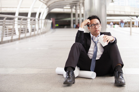 Stressful businessman or engineer sitting outdoor thoughtful thinking with hopelessの写真素材